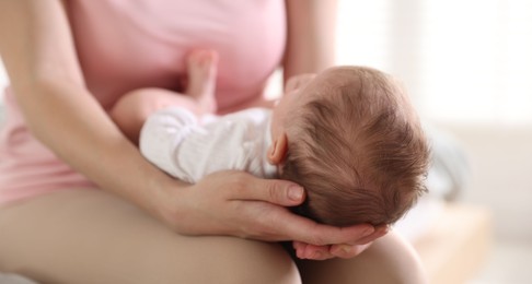 Photo of Mom holding her sleeping newborn baby at home, closeup