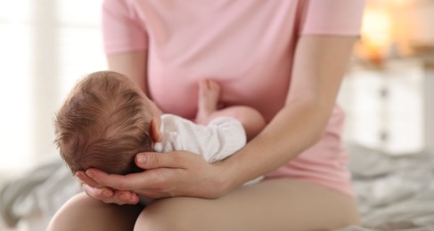 Photo of Mom holding her sleeping newborn baby at home, closeup