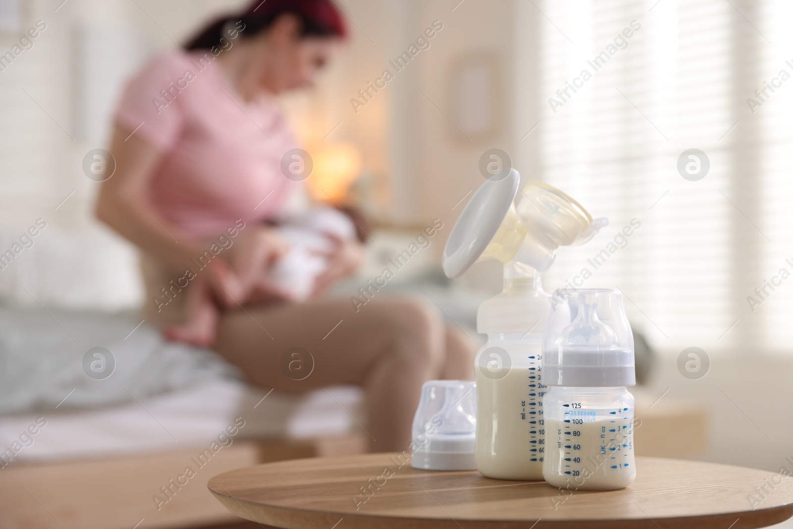 Breast pump and bottle with milk on table. Mother breastfeeding her baby at home, selective focus Photo of Breast pump and bottle with milk on table. Mother breastfeeding her baby at home, selective focus