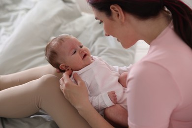 Photo of Mother putting her cute newborn baby to sleep on bed at home, closeup