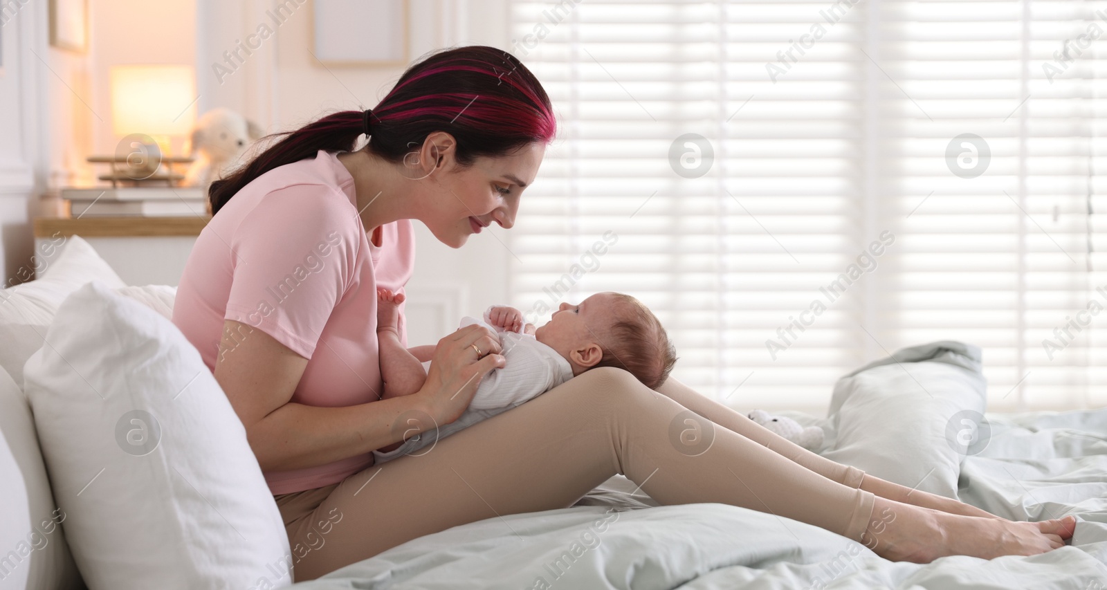 Mother putting her cute newborn baby to sleep on bed at home Photo of Mother putting her cute newborn baby to sleep on bed at home