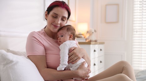 Photo of Mother putting her cute newborn baby to sleep on bed at home