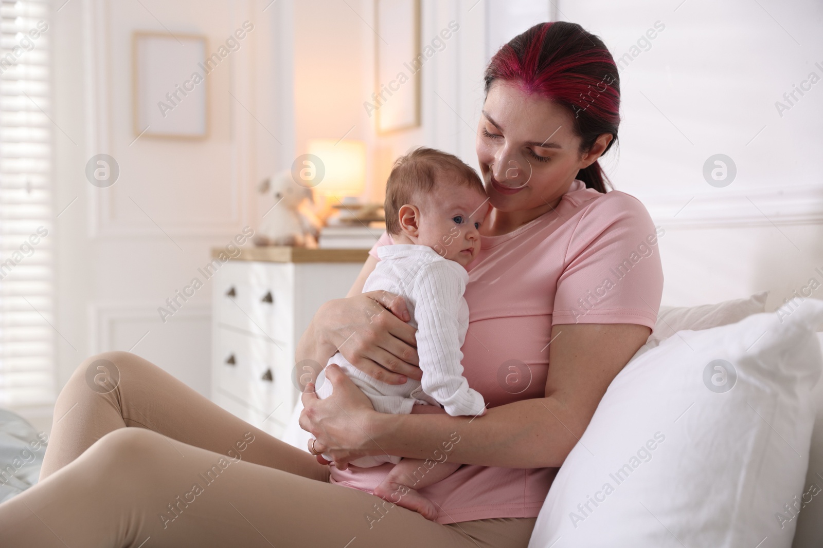 Mother putting her cute newborn baby to sleep on bed at home Photo of Mother putting her cute newborn baby to sleep on bed at home