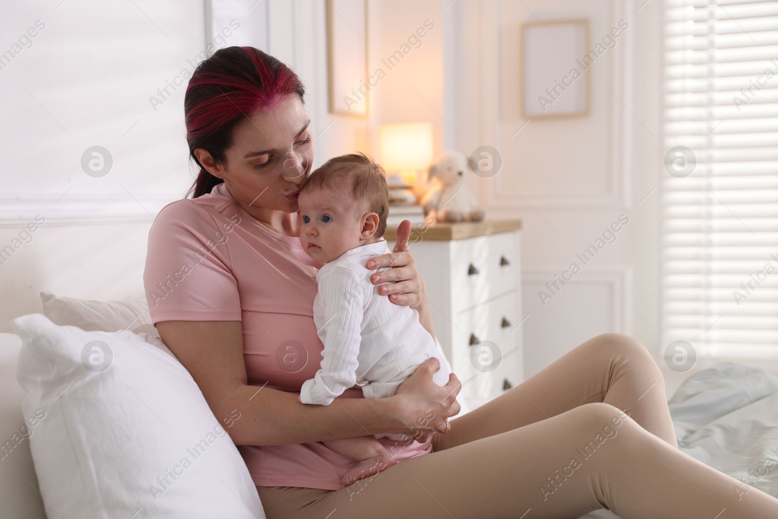 Mother putting her cute newborn baby to sleep on bed at home Photo of Mother putting her cute newborn baby to sleep on bed at home