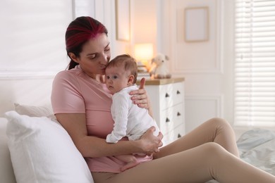 Photo of Mother putting her cute newborn baby to sleep on bed at home