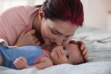 Photo of Mother putting her cute newborn baby to sleep on bed at home, closeup