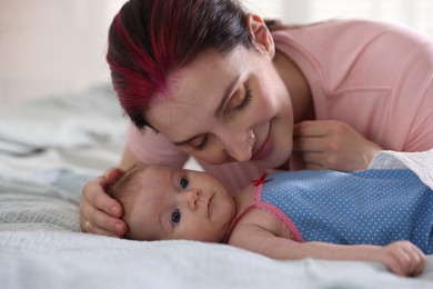 Photo of Mother putting her cute newborn baby to sleep on bed at home, closeup