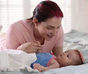 Photo of Mother putting her cute newborn baby to sleep on bed at home