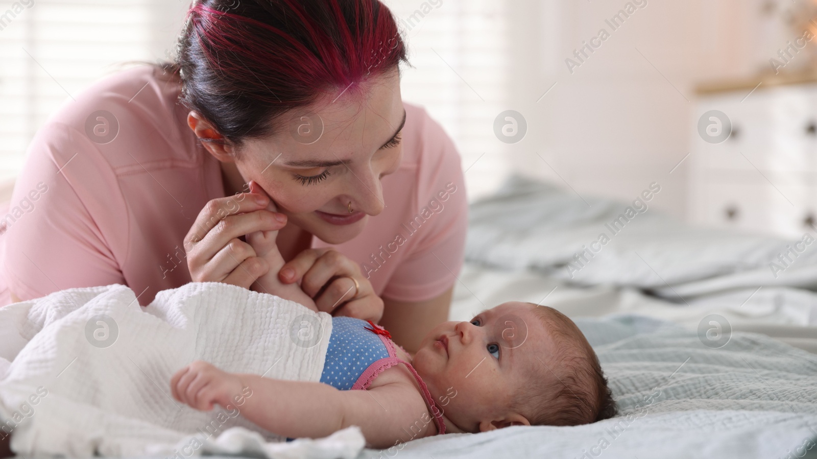 Mother putting her cute newborn baby to sleep on bed at home Photo of Mother putting her cute newborn baby to sleep on bed at home