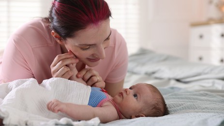 Photo of Mother putting her cute newborn baby to sleep on bed at home