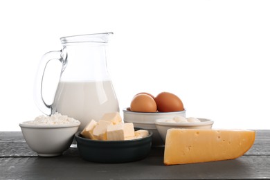 Photo of Different dairy products and eggs on grey wooden table against white background