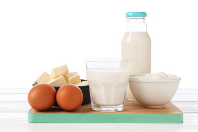 Photo of Different dairy products and eggs on wooden table against white background