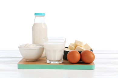 Photo of Different dairy products and eggs on wooden table against white background