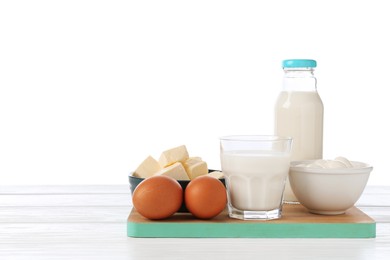 Photo of Different dairy products and eggs on wooden table against white background