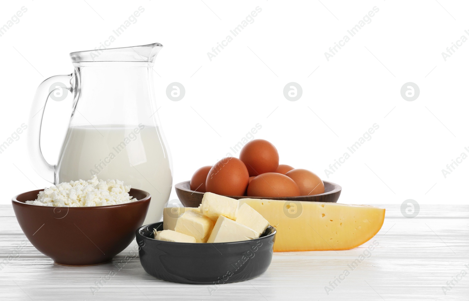Different dairy products and eggs on wooden table against white background Photo of Different dairy products and eggs on wooden table against white background