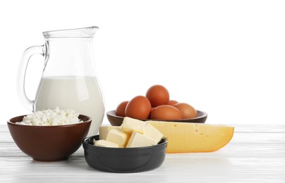 Photo of Different dairy products and eggs on wooden table against white background