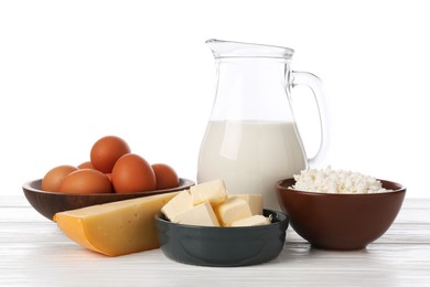 Photo of Different dairy products and eggs on wooden table against white background
