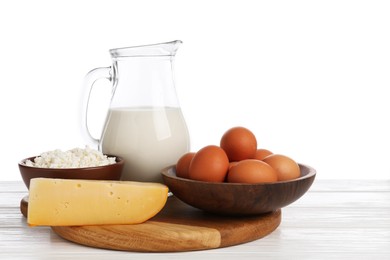 Photo of Different dairy products and eggs on wooden table against white background