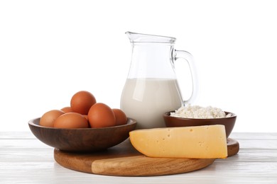 Photo of Different dairy products and eggs on wooden table against white background