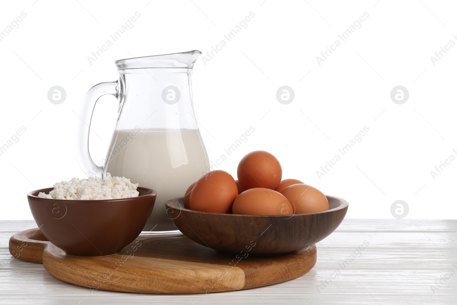 Milk, cottage cheese and eggs on wooden table against white background Photo of Milk, cottage cheese and eggs on wooden table against white background