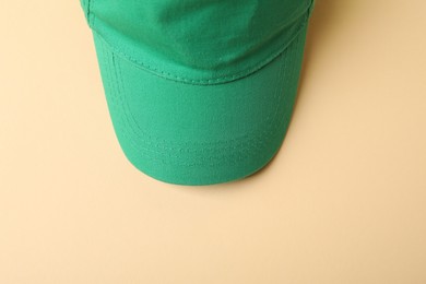 Photo of Green baseball hat on beige background, top view
