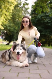 Photo of Happy woman with her cute Alaskan malamute dog in park