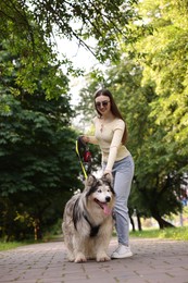 Photo of Happy woman with her cute Alaskan malamute dog in park, low angle view