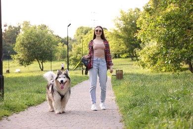 Photo of Happy woman walking with her cute Alaskan malamute dog in park