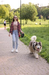 Photo of Happy woman walking with her cute Alaskan malamute dog in park