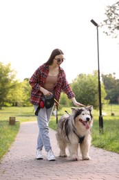 Photo of Happy woman walking with her cute Alaskan malamute dog in park