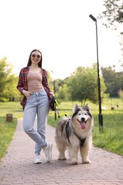 Photo of Happy woman walking with her cute Alaskan malamute dog in park