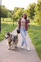 Photo of Happy woman walking with her cute Alaskan malamute dog in park