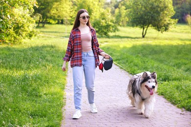 Photo of Woman walking with her cute Alaskan malamute dog in park