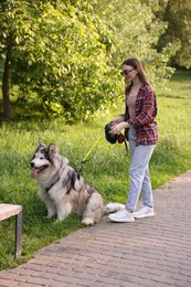Photo of Happy woman with her cute Alaskan malamute dog in park
