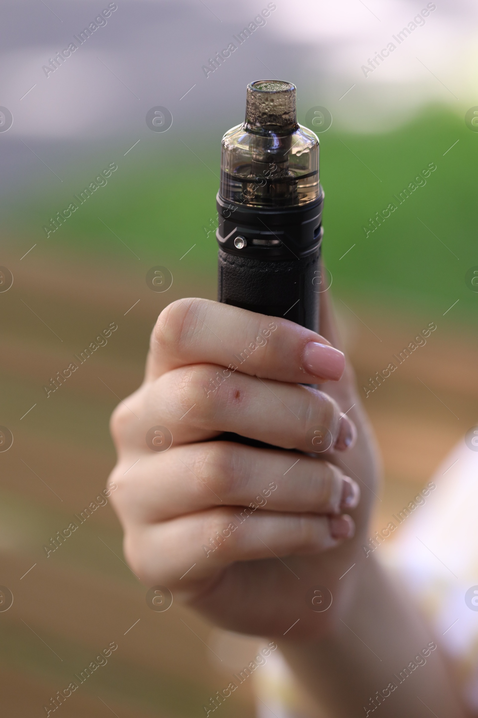 Young woman with electronic smoking device outdoors, closeup Photo of Young woman with electronic smoking device outdoors, closeup
