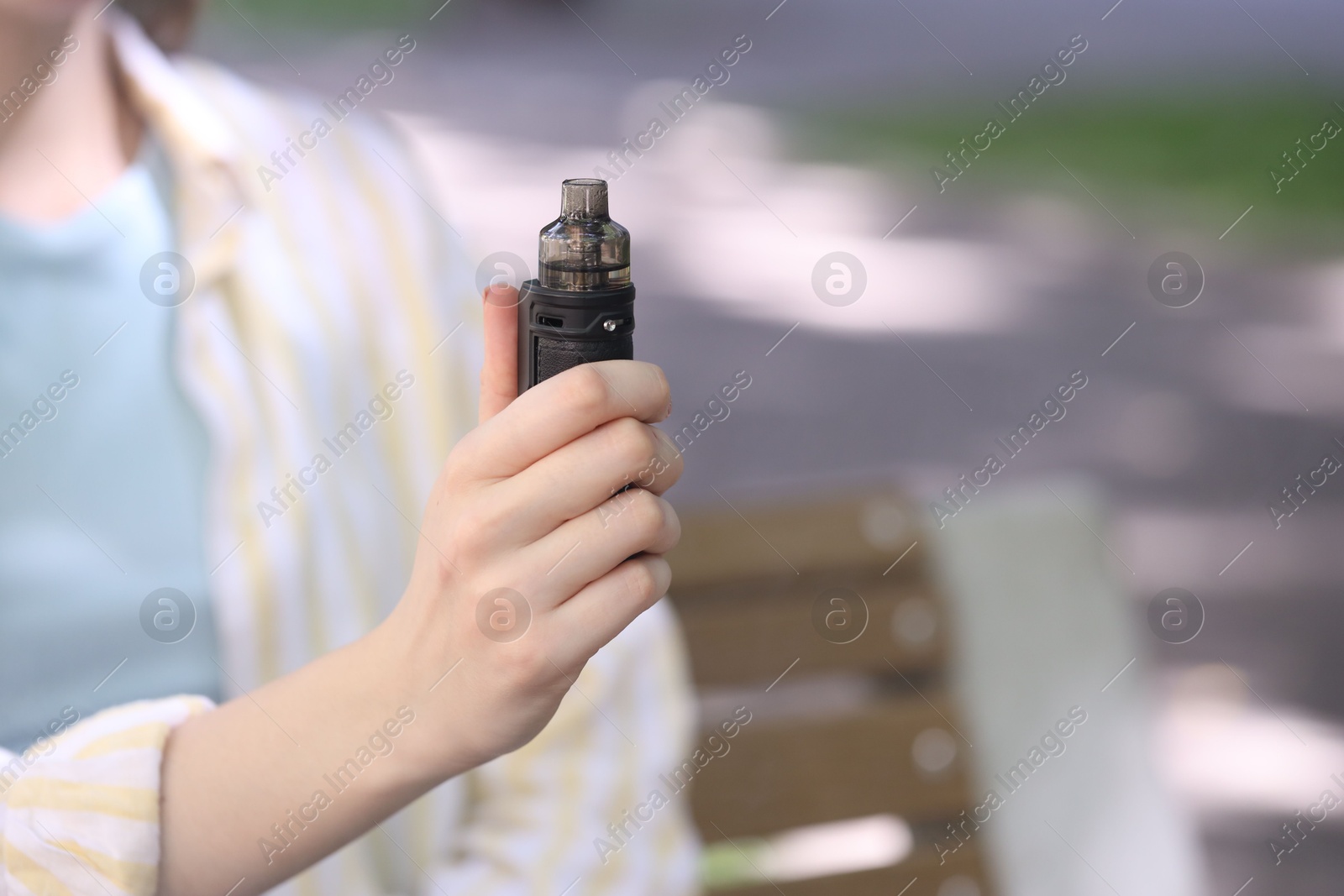 Young woman with electronic smoking device outdoors, closeup. Space for text Photo of Young woman with electronic smoking device outdoors, closeup. Space for text