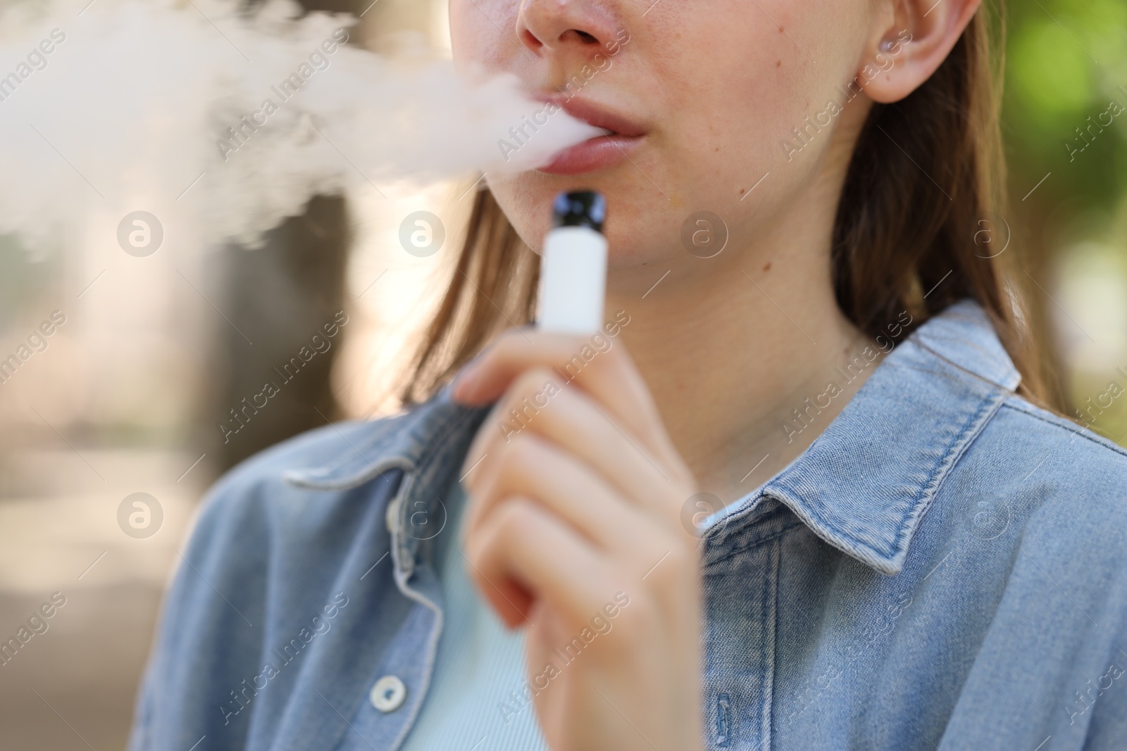 Young woman using electronic smoking device outdoors, closeup Photo of Young woman using electronic smoking device outdoors, closeup