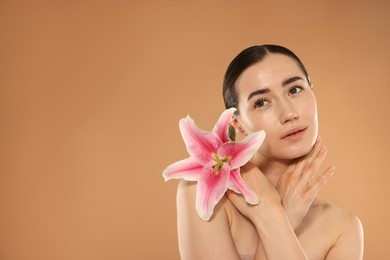 Photo of Beautiful woman after spa treatment with lily flower on beige background. Space for text