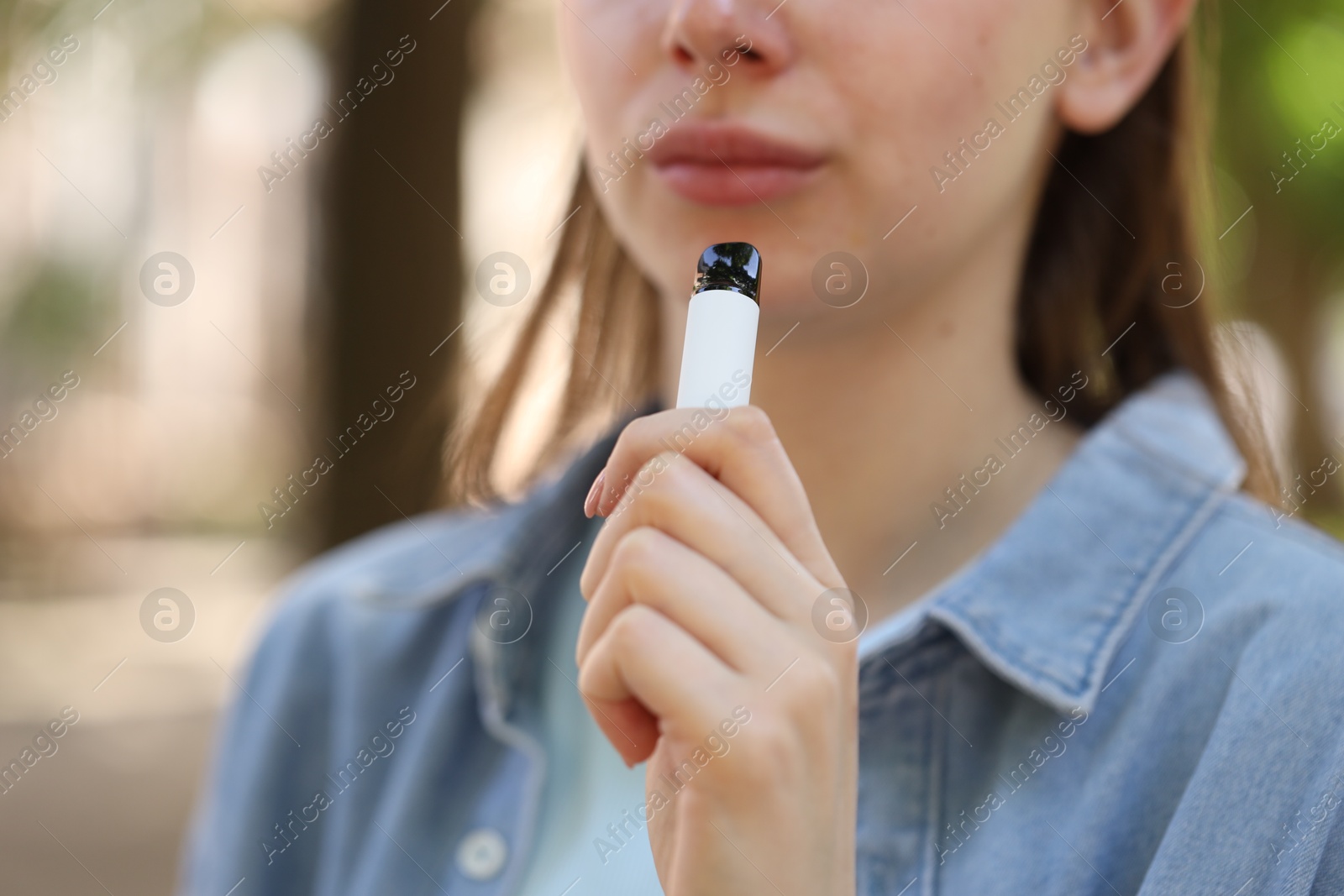 Young woman using electronic smoking device outdoors, closeup Photo of Young woman using electronic smoking device outdoors, closeup
