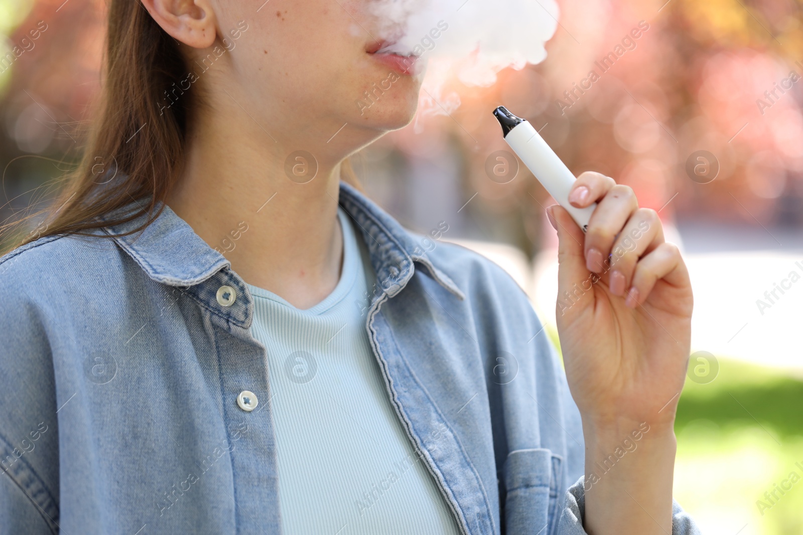 Young woman using electronic smoking device outdoors, closeup Photo of Young woman using electronic smoking device outdoors, closeup