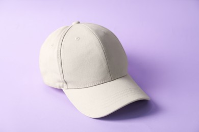 Photo of One beige baseball hat on violet background