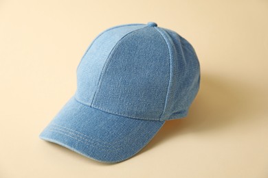 Photo of Denim baseball hat on beige background, closeup