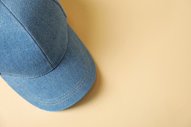 Photo of Denim baseball hat on beige background, top view. Space for text