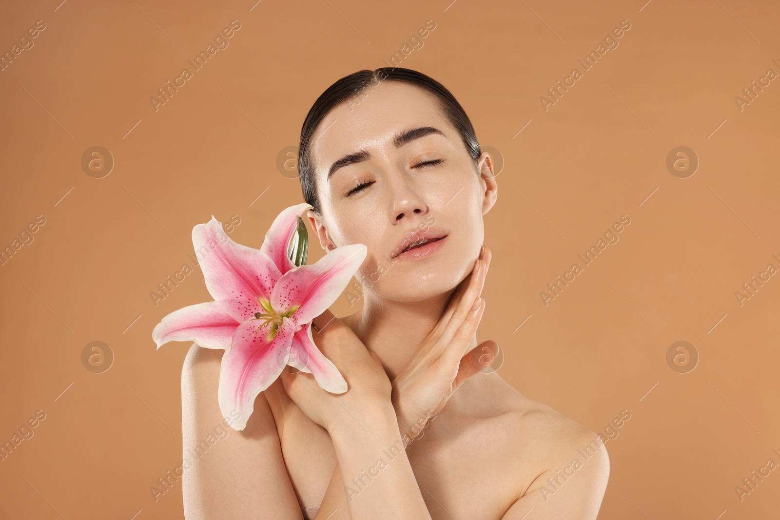 Beautiful woman after spa treatment with lily flower on beige background Photo of Beautiful woman after spa treatment with lily flower on beige background