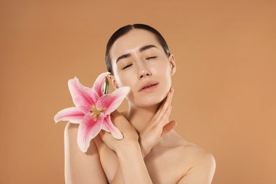 Photo of Beautiful woman after spa treatment with lily flower on beige background