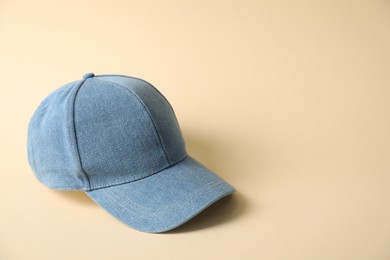 Photo of Denim baseball hat on beige background, space for text