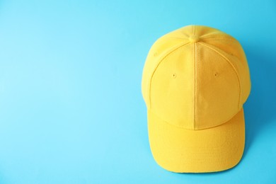Photo of Yellow baseball hat on light blue background, above view. Space for text