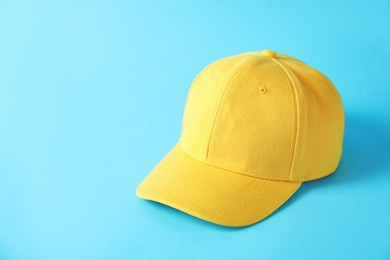 Photo of Yellow baseball hat on light blue background, space for text