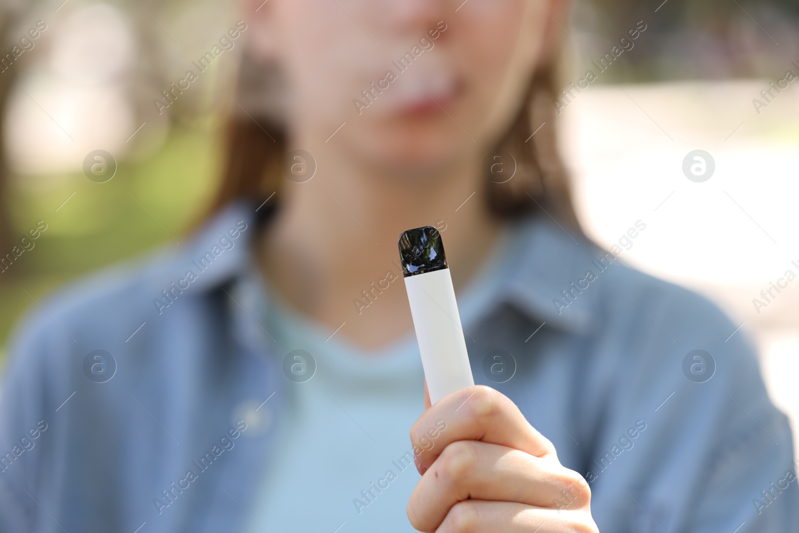Young woman using electronic smoking device outdoors, closeup Photo of Young woman using electronic smoking device outdoors, closeup