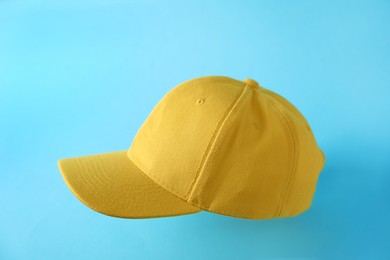 Photo of Yellow baseball hat in air on light blue background